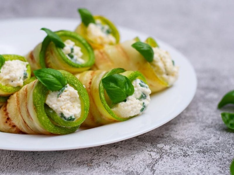 Ein weißer Teller mit Zucchini-Ricotta-Röllchen