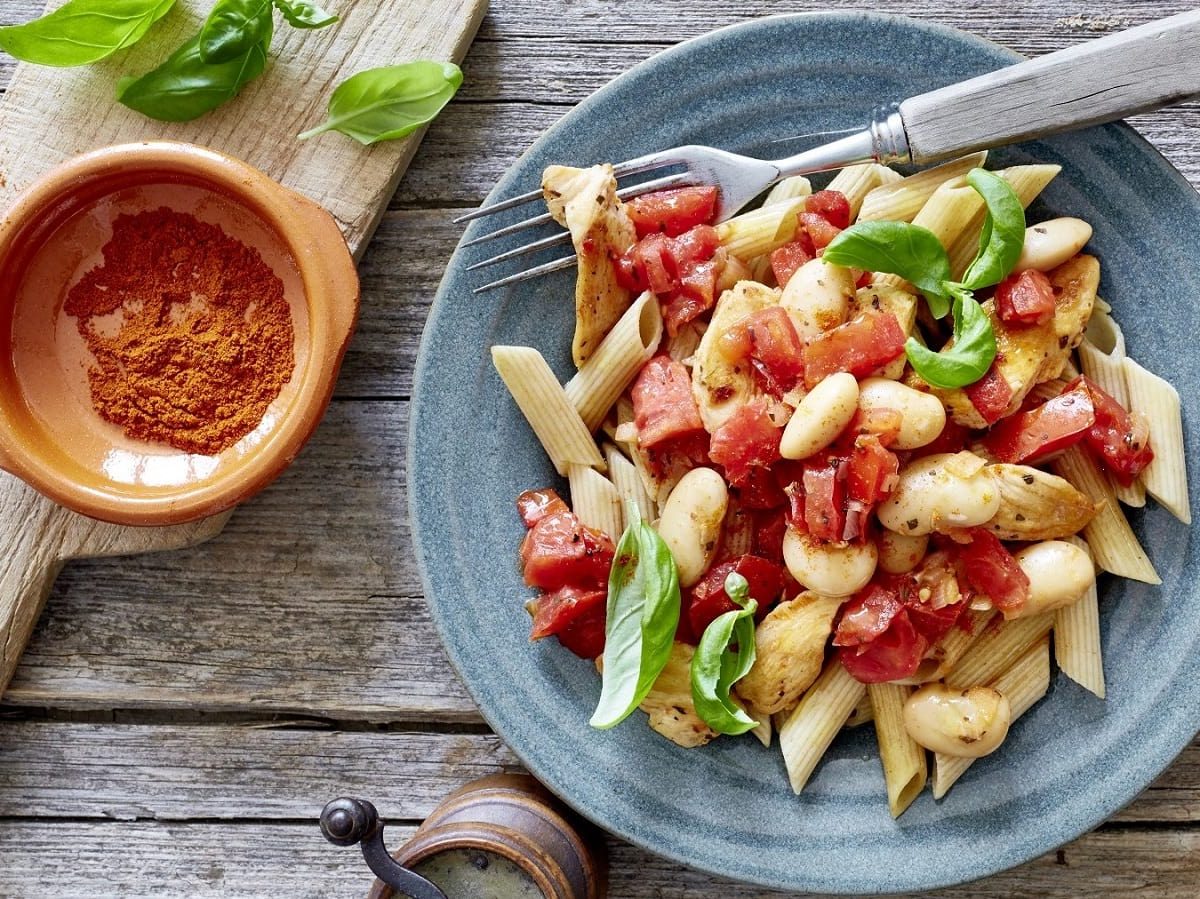 Auf einem Teller ist eine Portion Blitz-Penne angerichtet. Sie ist mit Basilikum garniert.