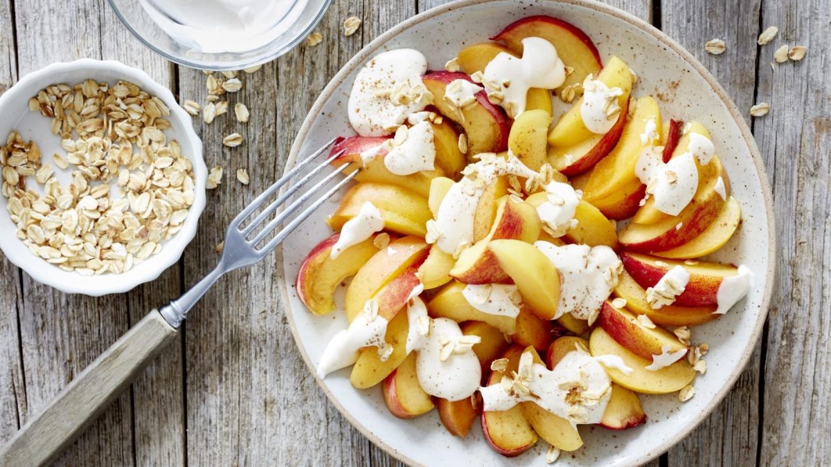 Einfache Frucht-Kombi aus Aprikose und Pfirsich, getoppt mit leichtem griechischem Joghurt und gerösteten Haferflocken.