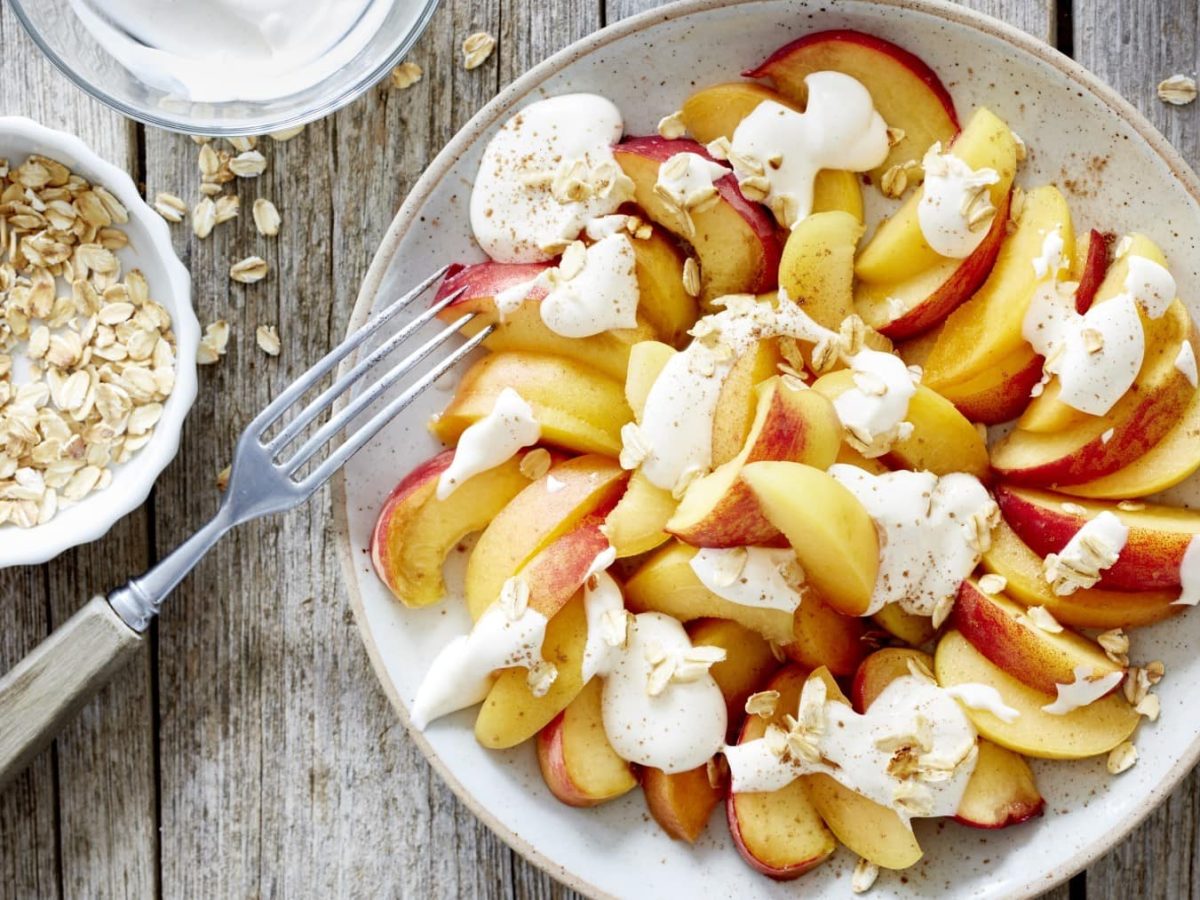 Einfache Frucht-Kombi aus Aprikose und Pfirsich, getoppt mit leichtem griechischem Joghurt und gerösteten Haferflocken.