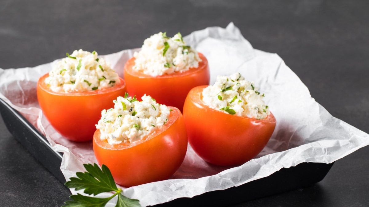 Gefüllte Tomaten mit Hüttenkäse auf mit Papier ausgelegtem Blech