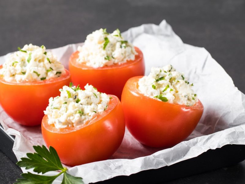 Gefüllte Tomaten mit Hüttenkäse auf mit Papier ausgelegtem Blech