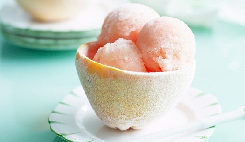 In einer Zitronenschale ist ein fruchtiges Grapefruit-Aperol-Sorbet serviert.