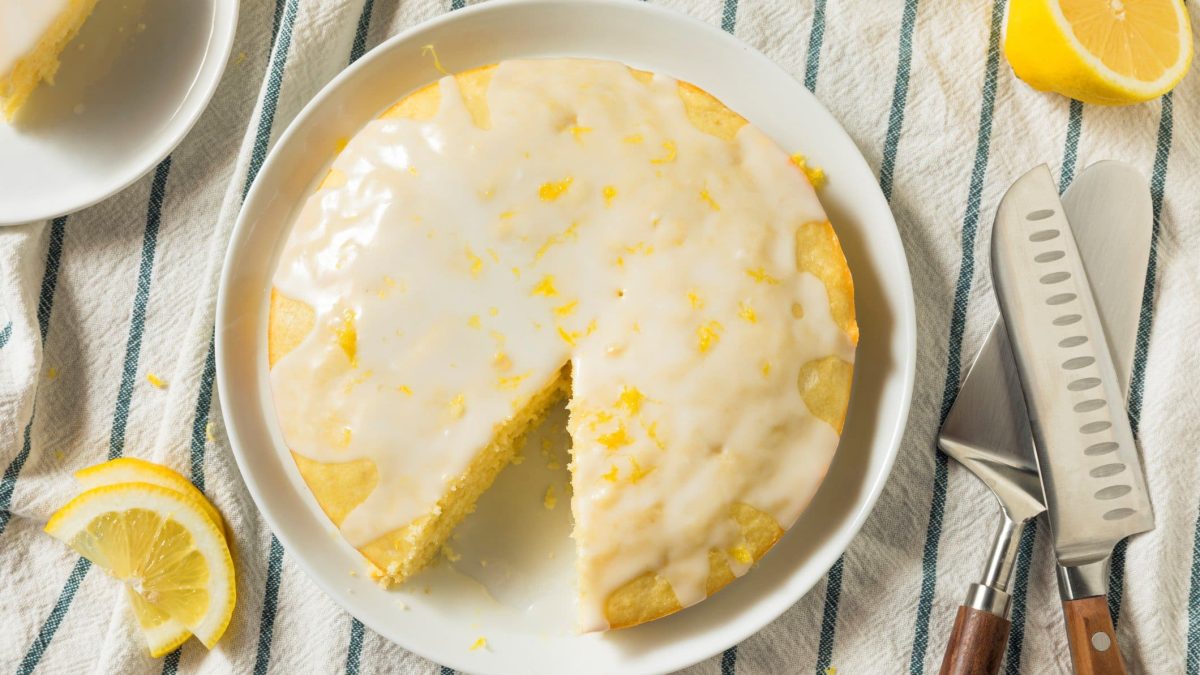 Limoncello-Kuchen mit Glasur auf gestreiftem Tischtuch.