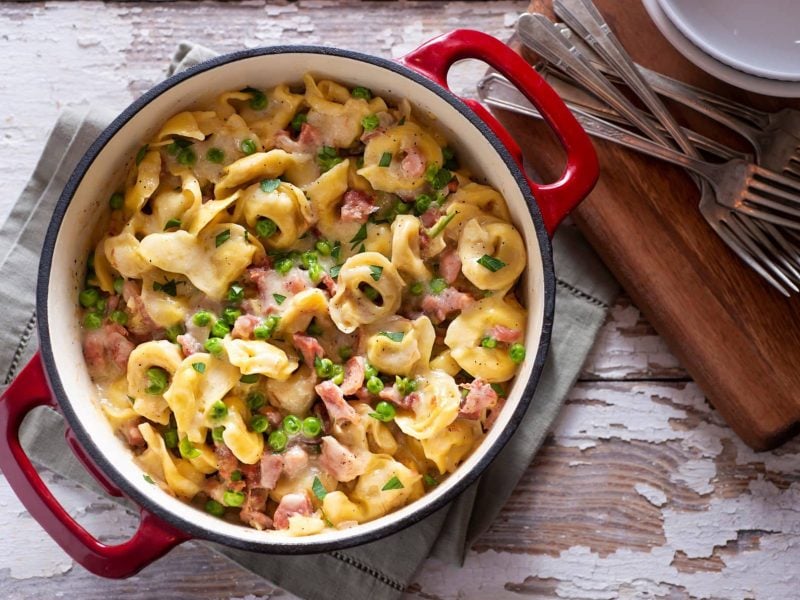 Kochtopf gefüllt mit One-Pot-Tortellini in Schinken-Sahne-Sauce mit Erbsen