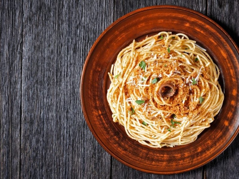 Pasta mollicata auf braunem Teller, angerichtet auf dunklem Holz.