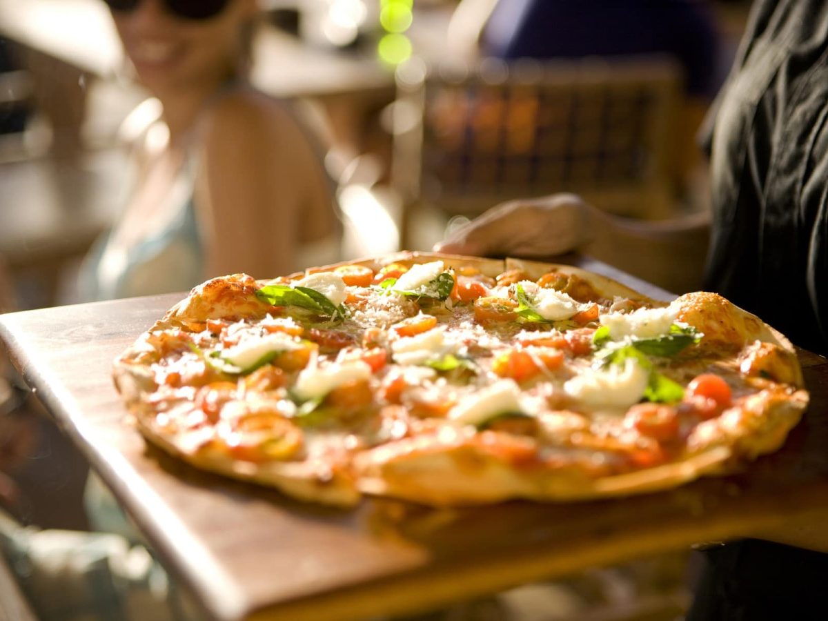 Frau serviert im Sonnenschein Pizza