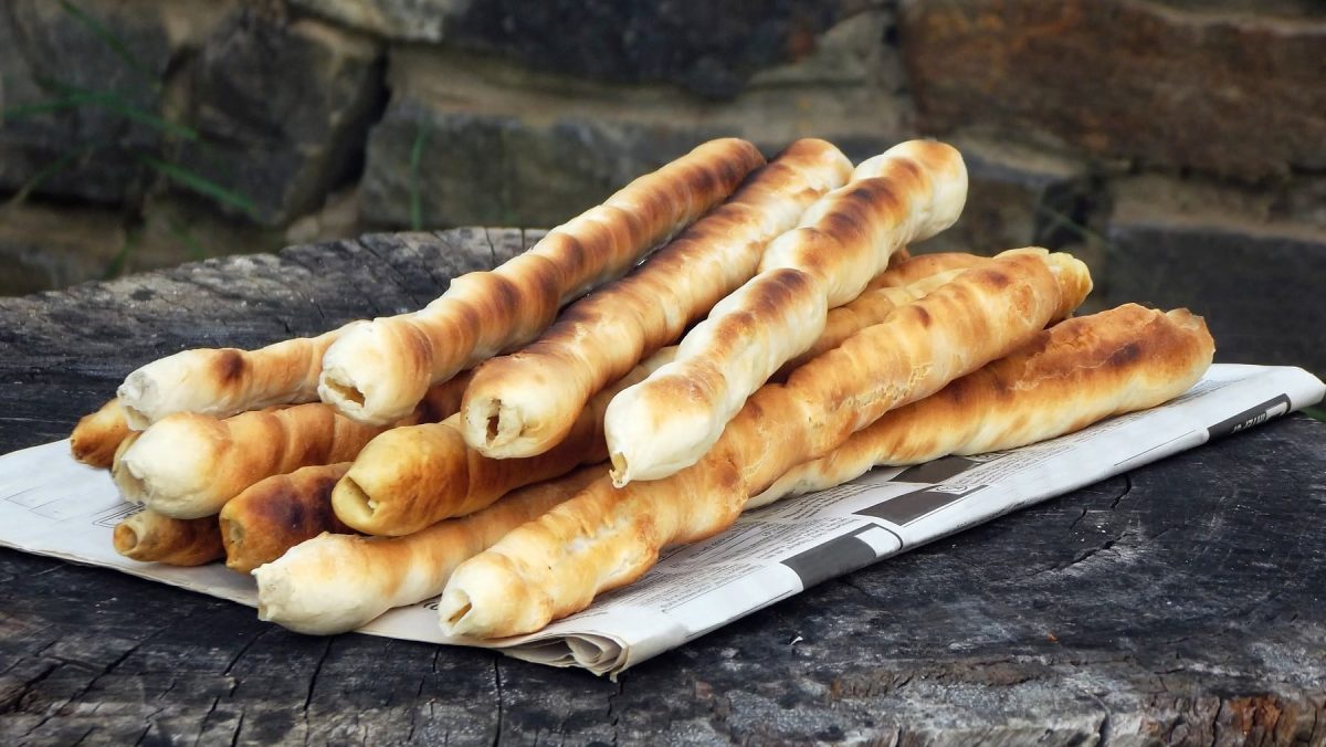 Einfaches über dem Feuer gebackenes Stockbrot, aufeinander geschichtet serviert auf einer Zeitung auf einem Holzblock.