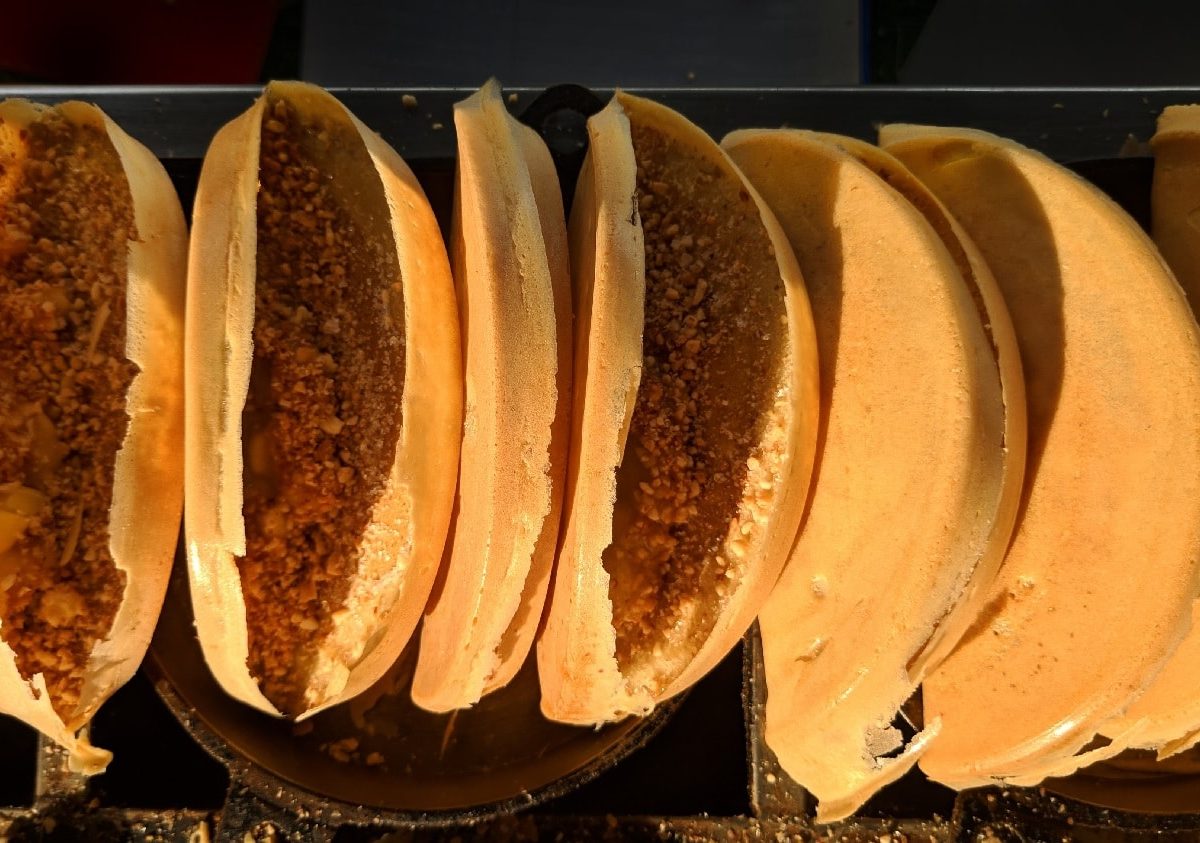 Mehrere Apam Balik aneinander gereiht an einem Streetfoodstand von oben fotografiert.