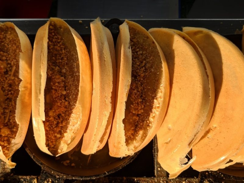 Mehrere Apam Balik aneinander gereiht an einem Streetfoodstand von oben fotografiert.