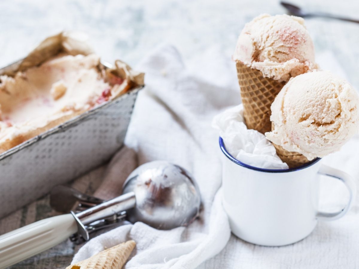 Eis selber machen: Zwei Eiswaffeln mit je einer Kugel Eis stehen in einer Tasse, daneben eine Kastenform mit selbst gemachtem Eis und ein Eisportionierer.