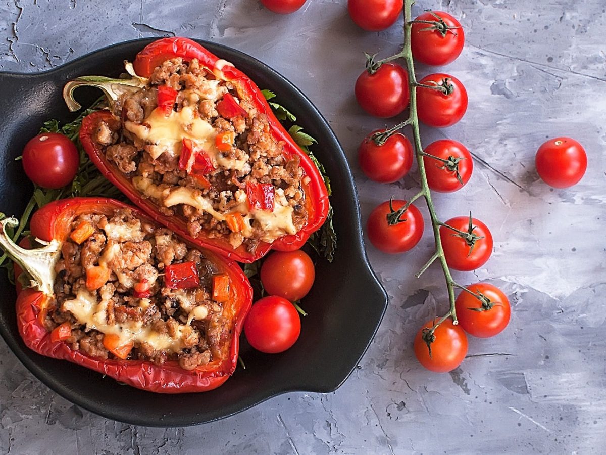 Gefüllte Paprika mit Hackfleisch überbacken mit Käse auf grauem Untergrund