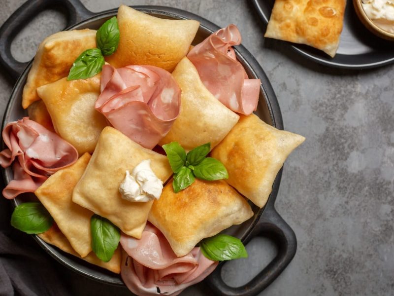 Ein schwarzer mit Teller Gnocco fritto auf grauem Hintergrund