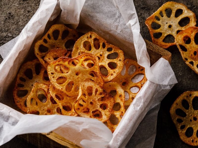 Frittierte Lotus-Chips in einer Holzbox auf etwas Papier