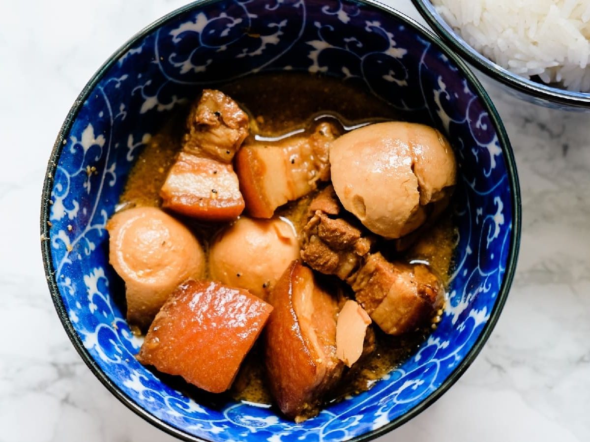 Thit Kho Trung in einer blauen Schüssel neben weißem Reis