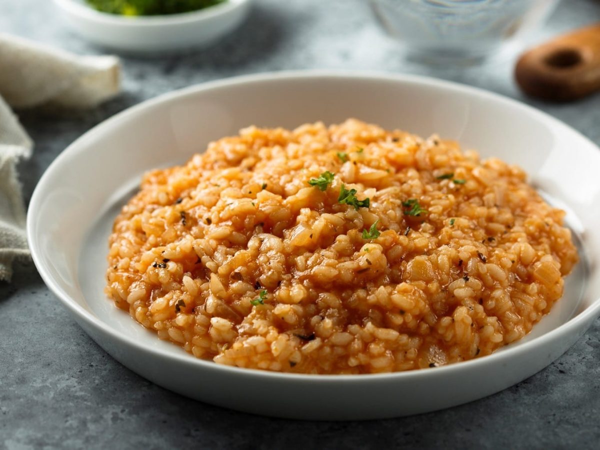 ein Teller veganes Tomatenrisotto mit frischen Kräutern bestreut.