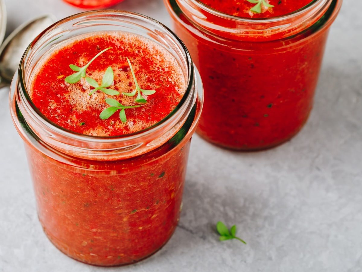 Zwei Gläser Wassermelonen-Gazpacho mit Kresse bestreut, daneben zwei Löffel.