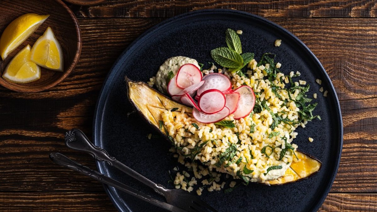 Zitronen-Minz-Tabouleh mit gegrillter Aubergine auf einem schwarzen Teller