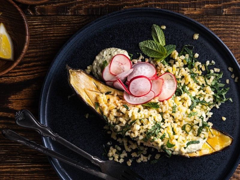 Zitronen-Minz-Tabouleh mit gegrillter Aubergine auf einem schwarzen Teller