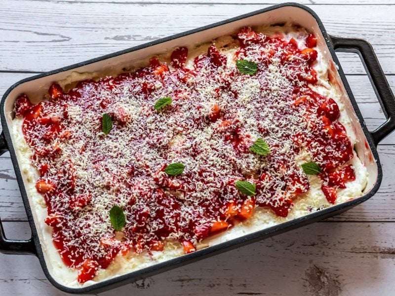 Erdbeerlasagne in schwarz-weißer Form auf hellem Holz.