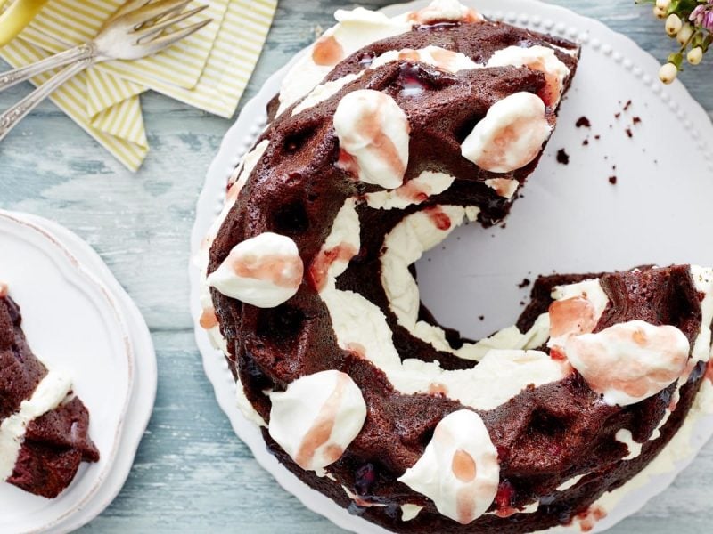 Auf einem weißen Teller liegt eine Kiba-Gugelhupftorte. Sie ist mit Sahne betupft und mit Creme gefüllt.