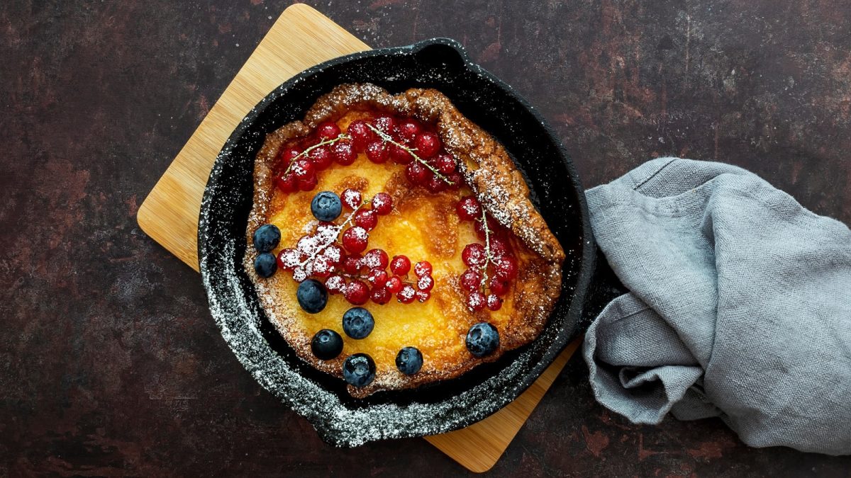 Eine schwarze gusseiserne Pfanne mit einem Dutch Baby und Beeren