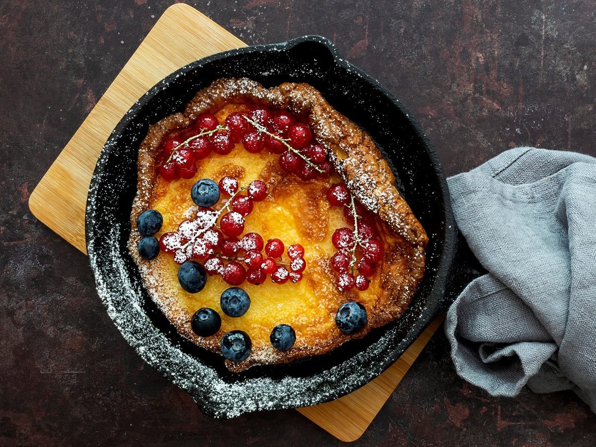 Eine schwarze gusseiserne Pfanne mit einem Dutch Baby und Beeren