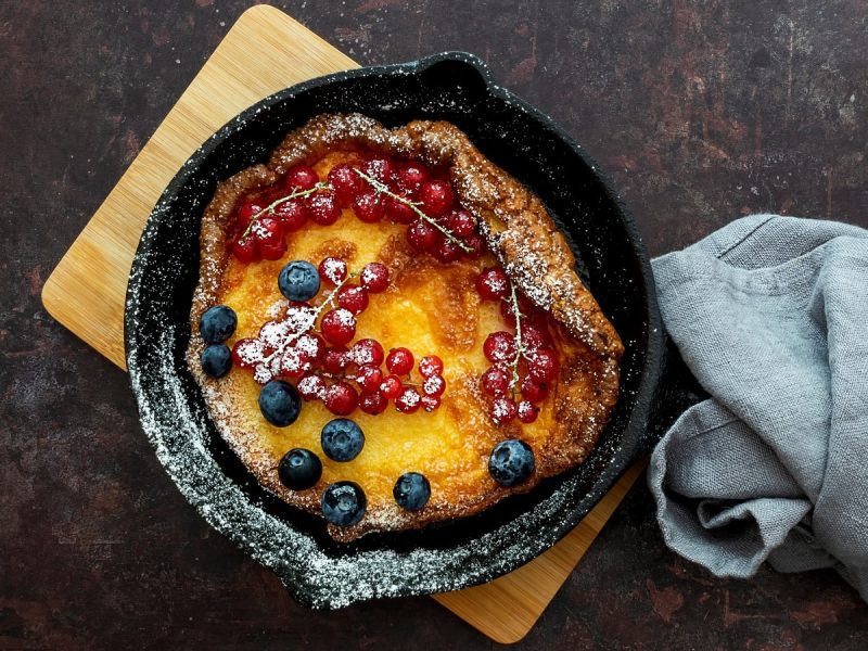 Eine schwarze gusseiserne Pfanne mit einem Dutch Baby und Beeren