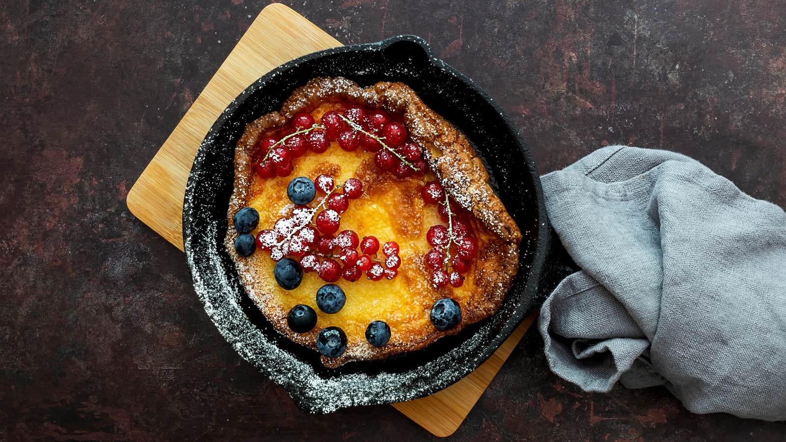 Eine schwarze gusseiserne Pfanne mit einem Dutch Baby und Beeren