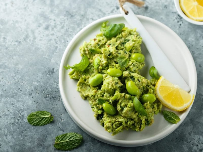 Ein Teller mit Edamame-Guacamole und Zitronenscheiben