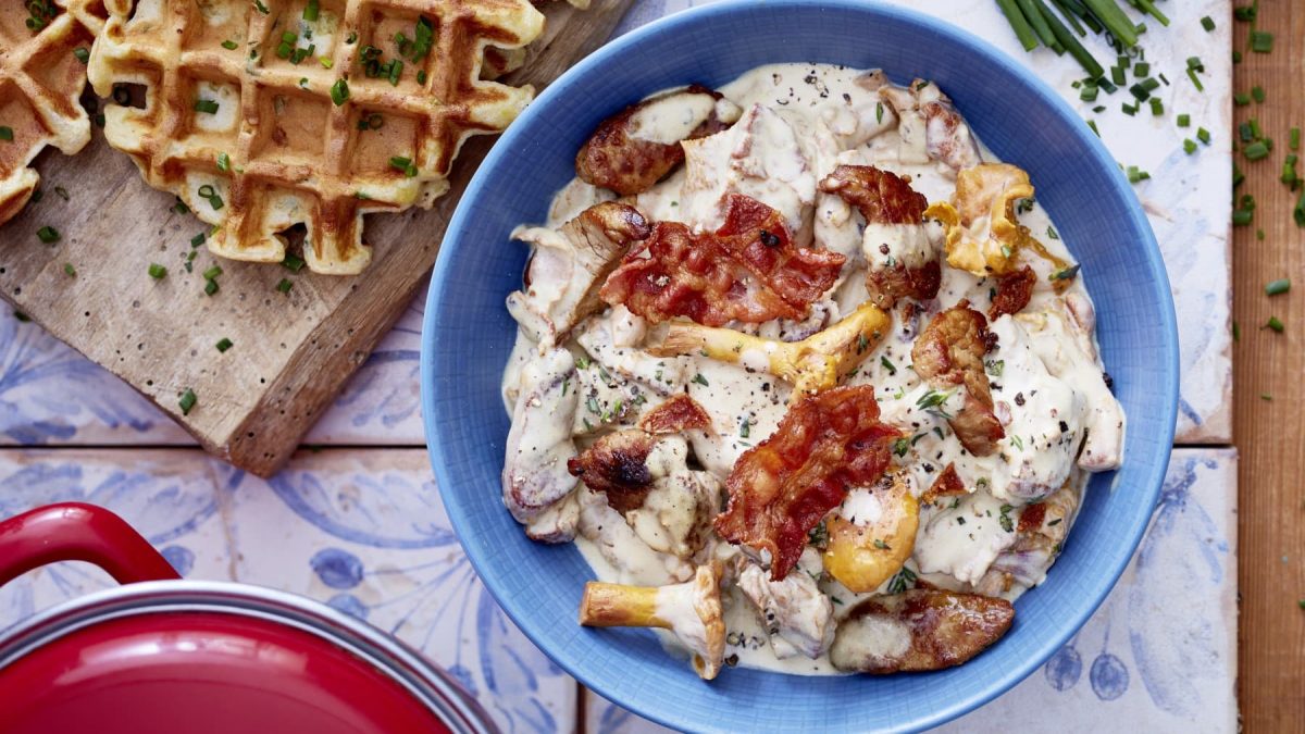 Filet-Gulasch in einer blauen Schale. Daneben Kartoffewaffeln auf einem Holzbrett.