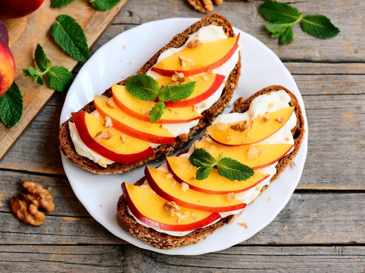 Ein weißer Teller mit Brot mit Nektarine und Ziegenfrischkäse