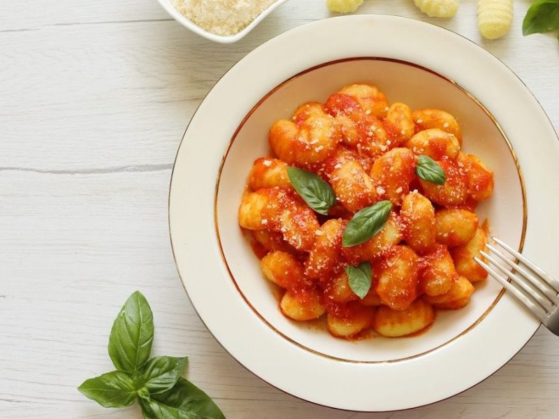 Auf einem Tisch steht ein Teller Gnocchi al pomodoro.