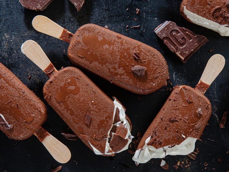 Selbst gemachte Eis am Stiel nach Magnum Art auf schwarzem Hintergrund. Eis teilweise angebrochen und Stücken von Schokolade. Aufnahme aus der Vogelperspektive.