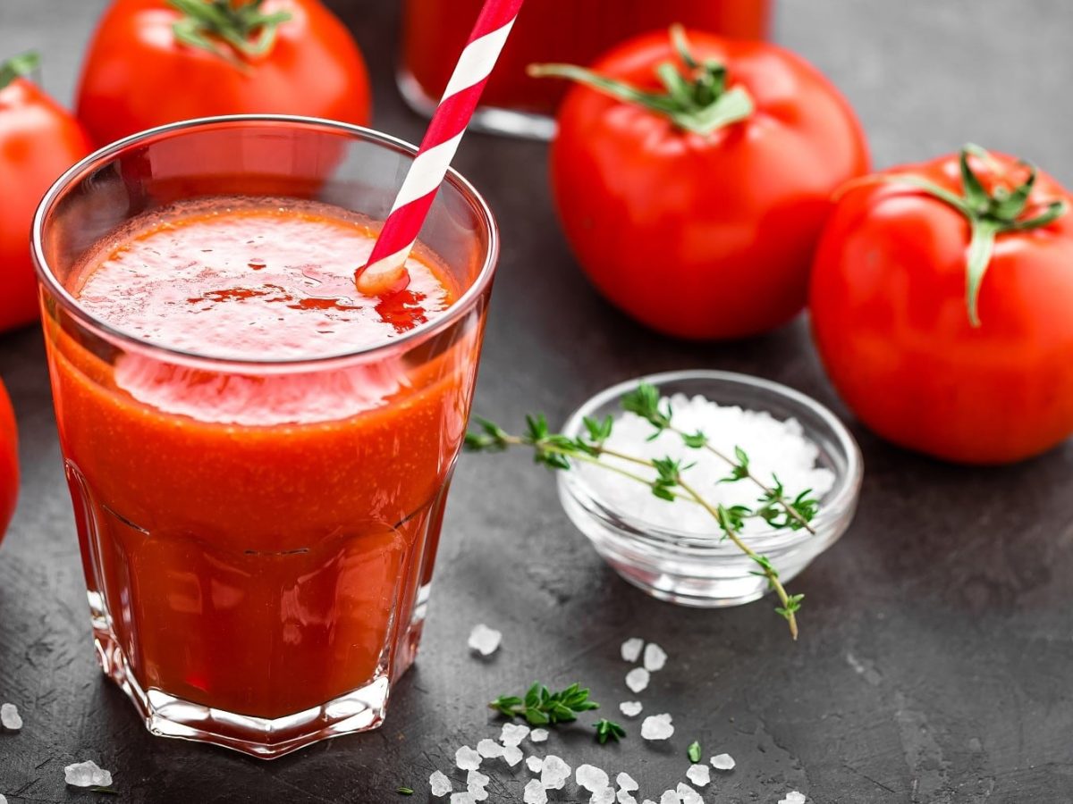 Tomatensaft selbst machen und in Gläser abfüllen, serviert mit Salz und Pfeffer auf einer Steinplatte.