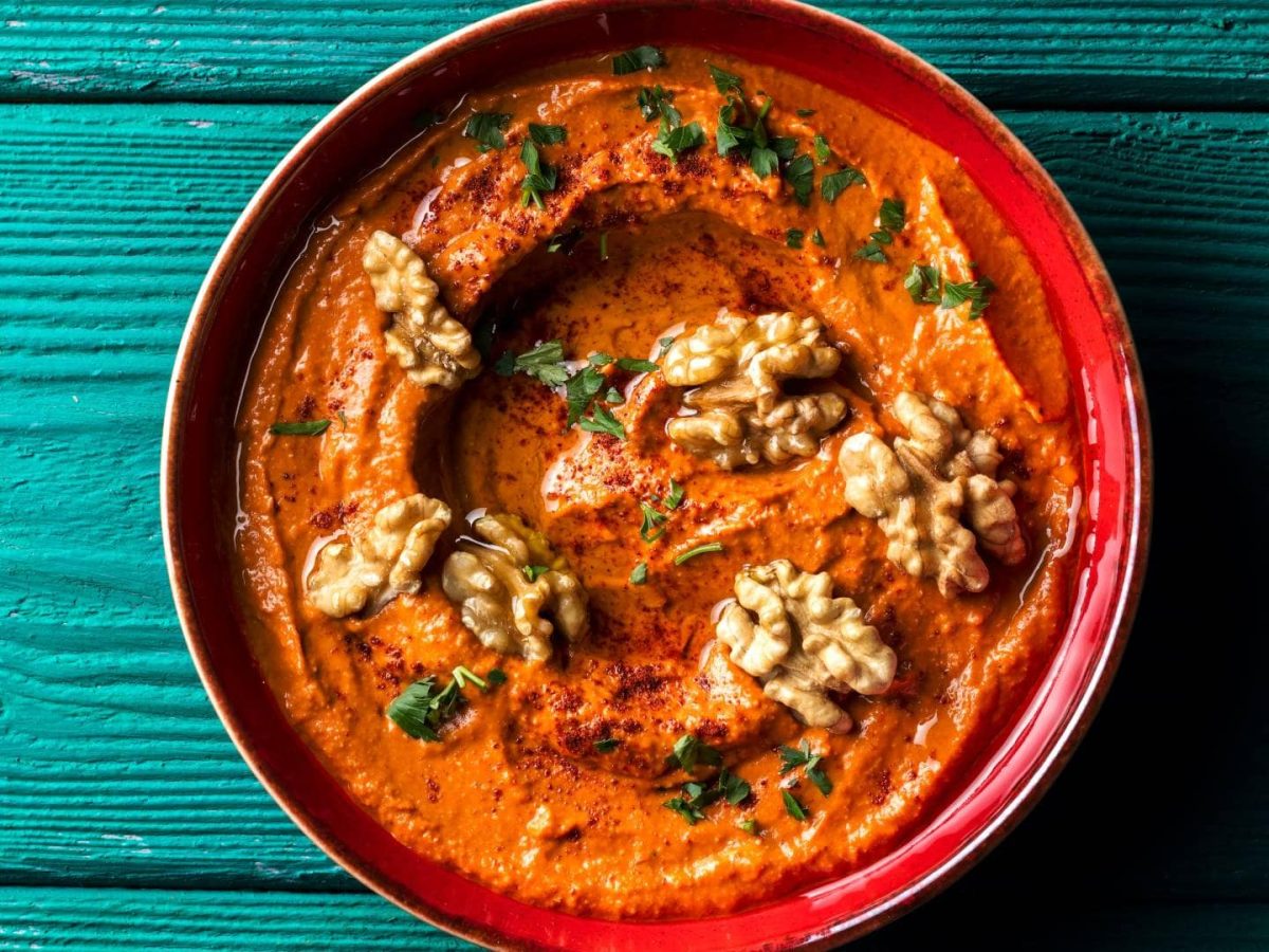 Eine Schüssel vegane Tomatenbutter mit Walnüssen und gehackten Kräutern in der Draufsicht.