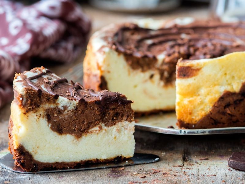 Ein Stück veganer russischer Zupfkuchen auf einem Tortenheber, dahinter steht der restliche Kuchen.