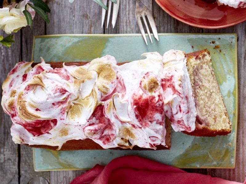 Auf einem Teller steht ein Beeren-Wölkchen Kuchen. Er ist mit Baiser bedeckt und leicht abgeflämmt.