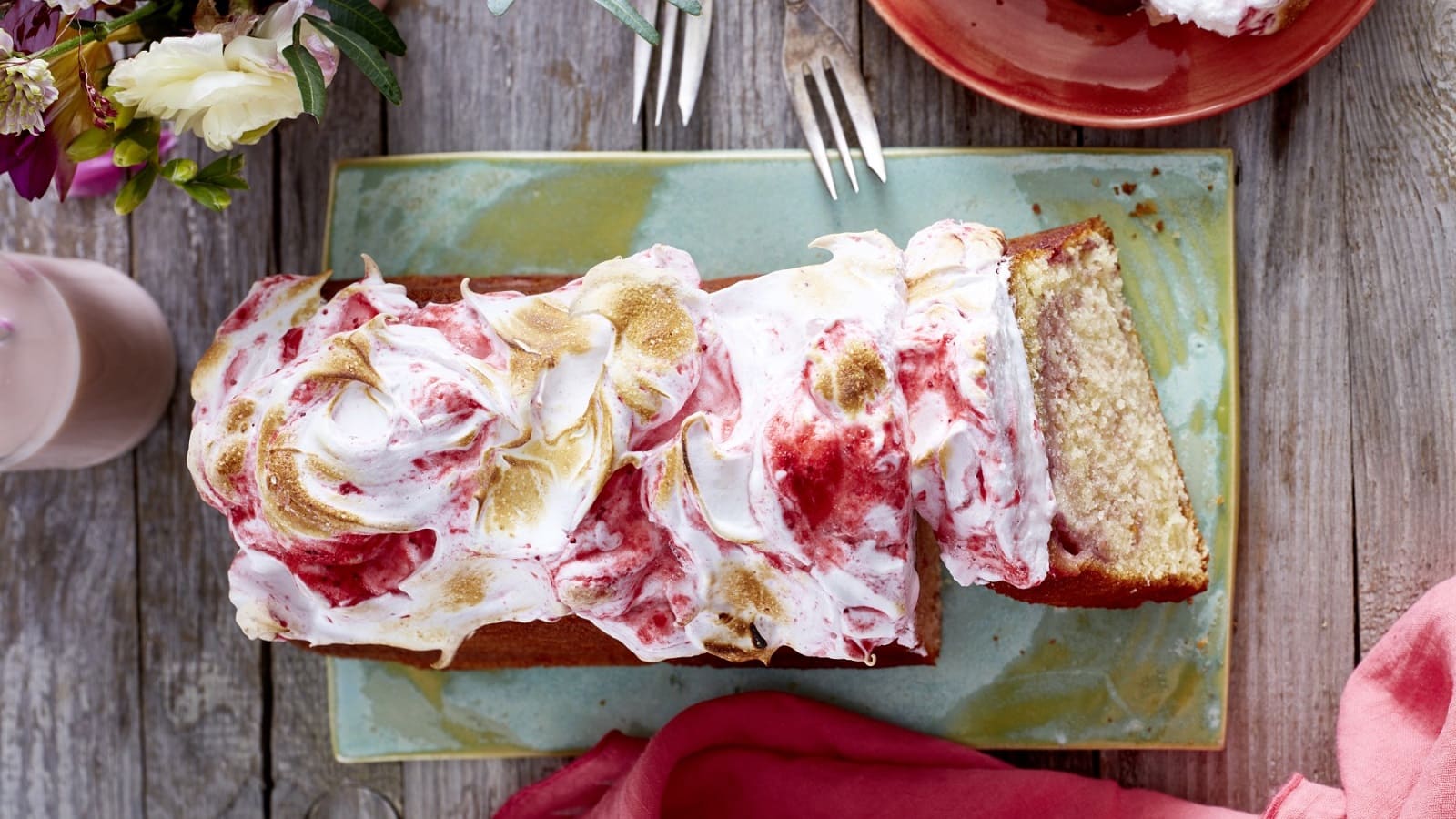 Auf einem Teller steht ein Beeren-Wölkchen Kuchen. Er ist mit Baiser bedeckt und leicht abgeflämmt.