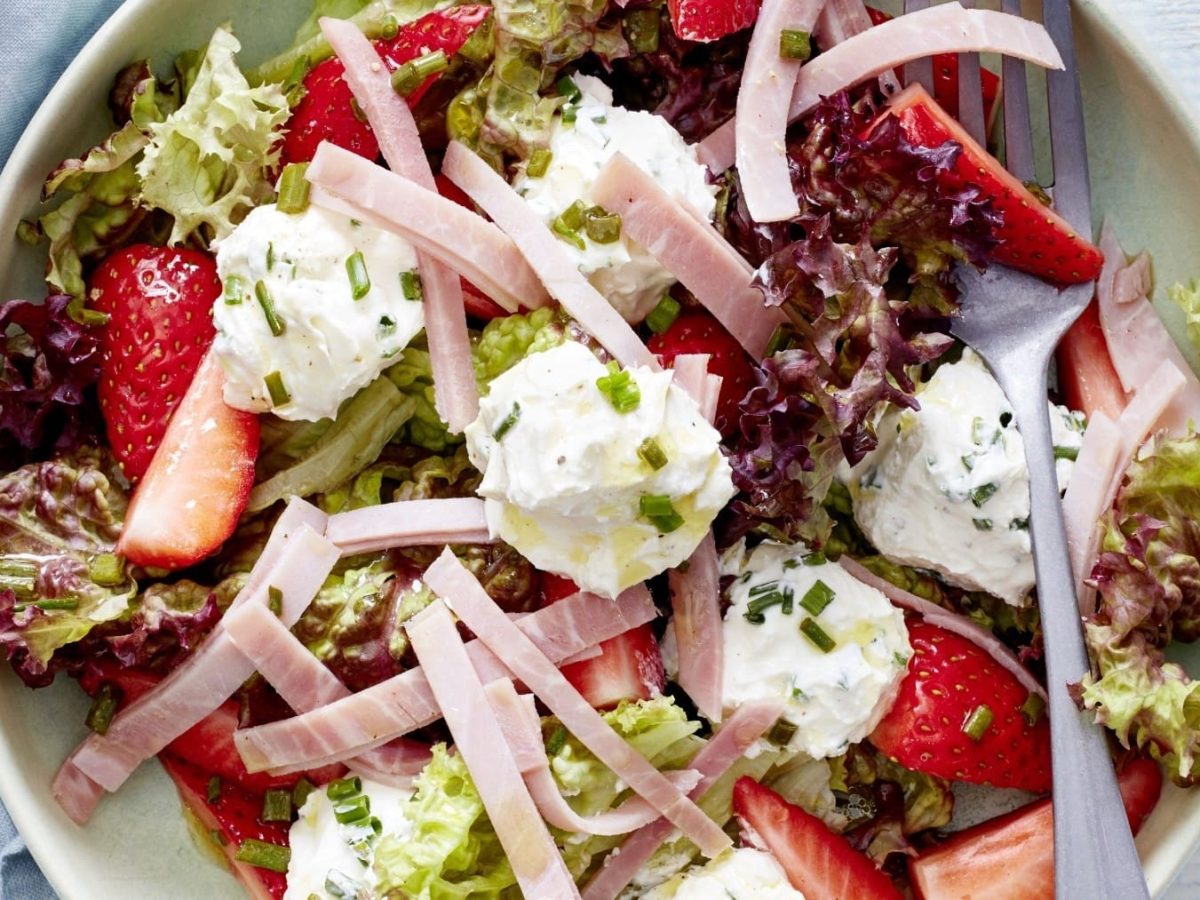 Erdbeersalat mit Frischkäse und Schinken, zusammengestellt in einer Salatbowl und garniert mit Schnittlauch und einer leichten Vinaigrette.