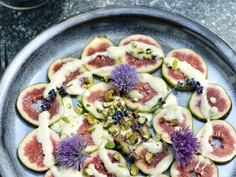 ein teller mit feigen und einer brie-vanille-sauce steht auf einem blauen Untergrund aus Holf.