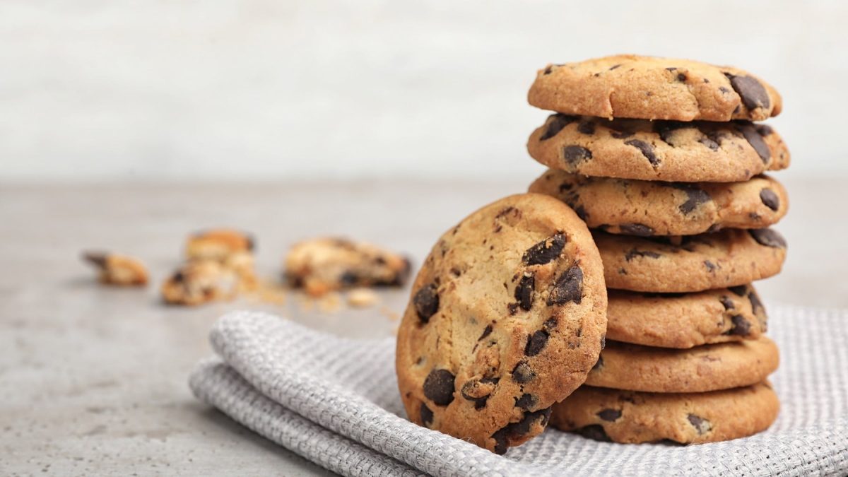 Ein Stapel glutenfreie vegane Kichererbsen-Erdnuss-Cookies mit Schoko-Chips auf einem Geschirrtuch.