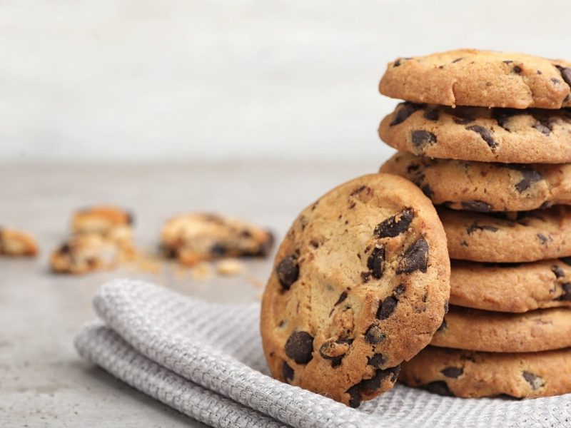 Ein Stapel glutenfreie vegane Kichererbsen-Erdnuss-Cookies mit Schoko-Chips auf einem Geschirrtuch.