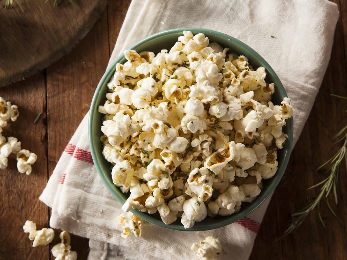 Eine Schüssel mit Knoblauch-Popcorn auf einem weißen Geschirrtuch.