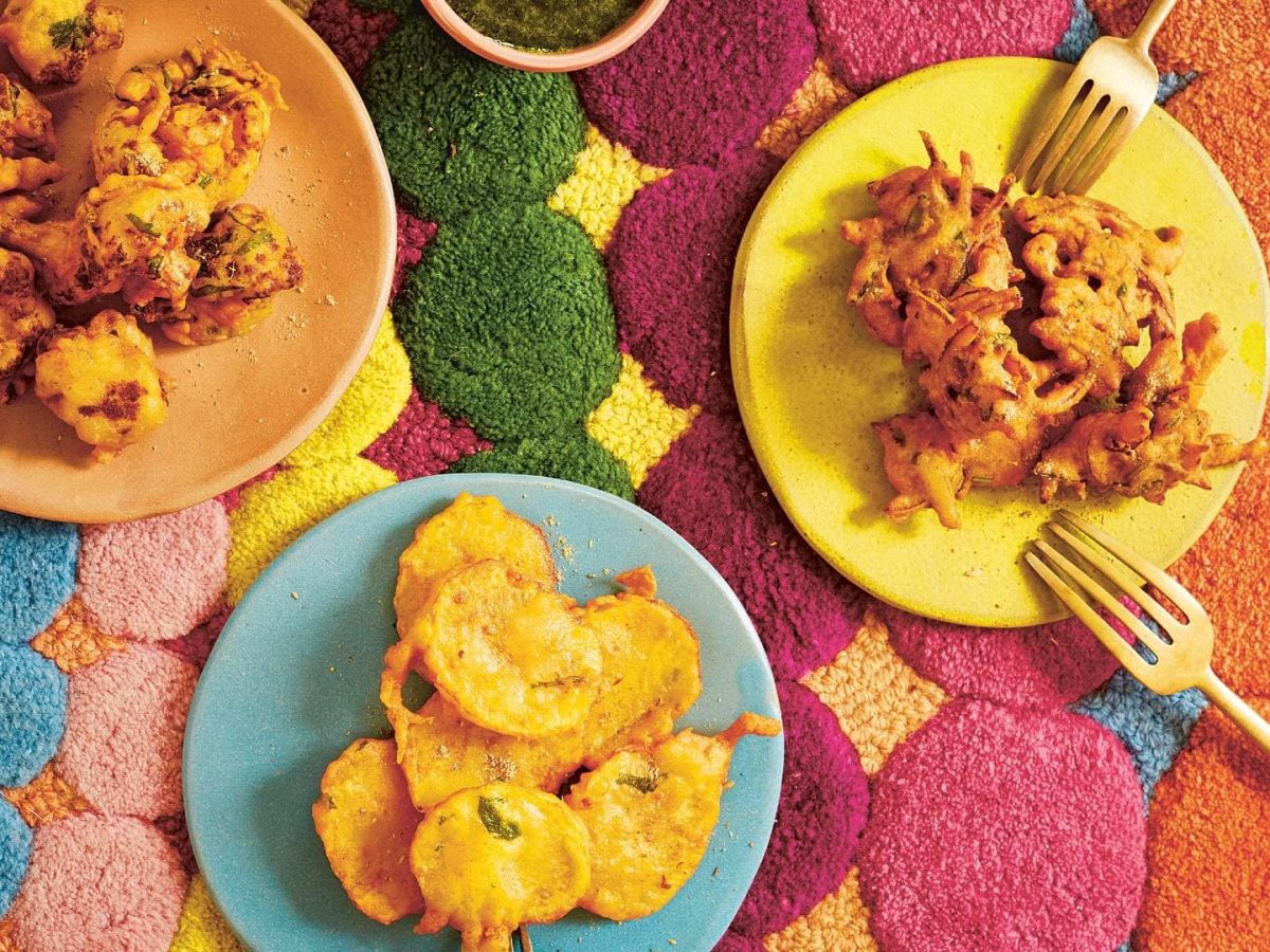 bunte Teller mit Pakoras, Gemüse im Teigmantel auf einem bunten Teppich in der Draufsicht.