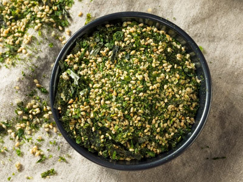 Eine schwarze Schüssel mit Furikake drinnen auf einem Leinentuch.