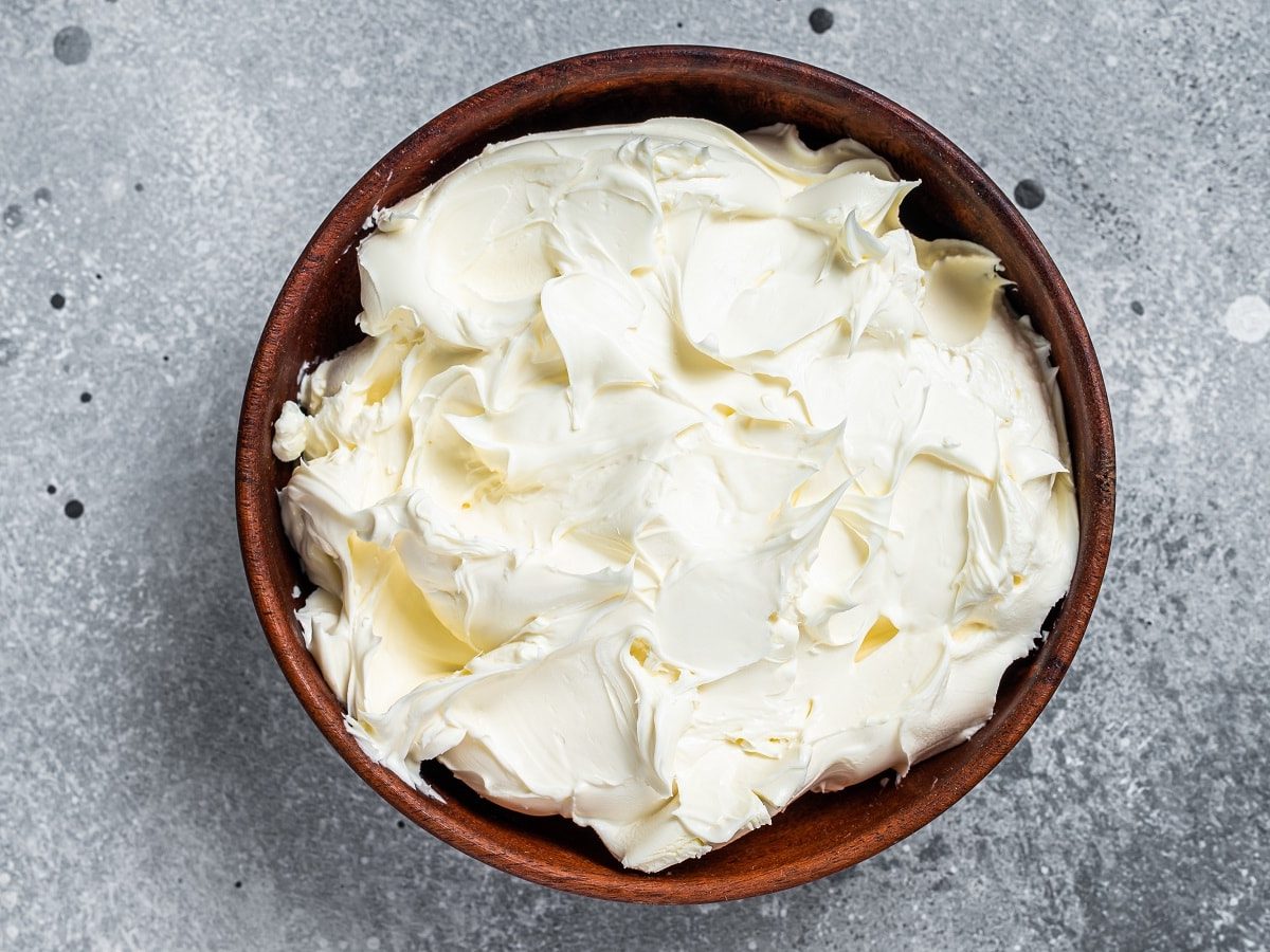 Eine holzfarbene Schüssel mit Mascarpone drinnen oder einer Mascarpone-Alternative.