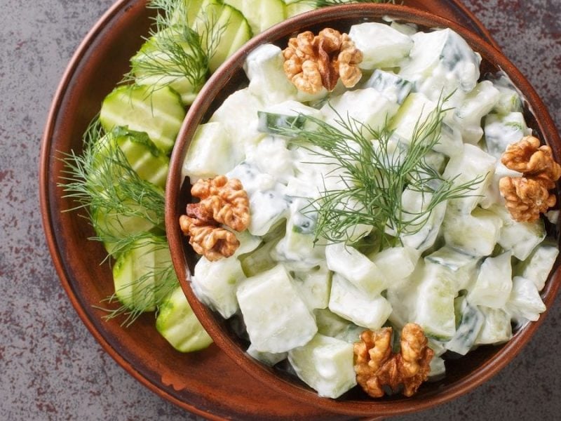 eine Schüssel mit Snezhanka steht auf einem tisch. es handelt sich um einen Gurkensalat mit Joghurt.