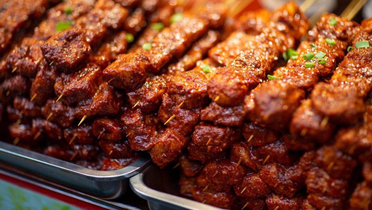 Gegrillte Tofu-Spieße Cajun-Style gestapelt auf Metallschalen auf einem Markt. Frontalansicht.