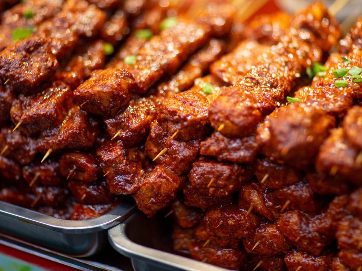 Gegrillte Tofu-Spieße Cajun-Style gestapelt auf Metallschalen auf einem Markt. Frontalansicht.